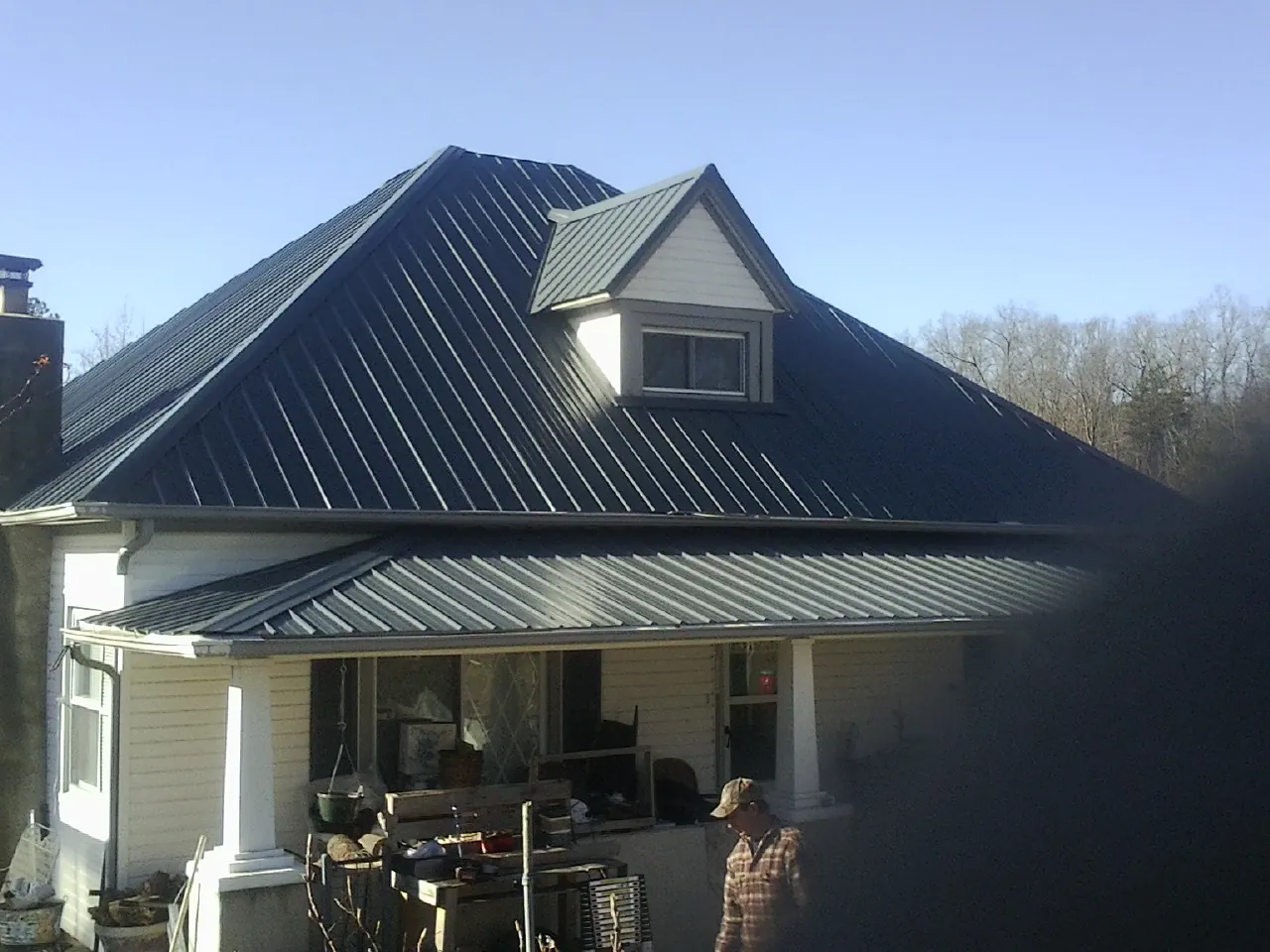 Dark blue standing seam metal roof with a dormer above a front porch in Webster